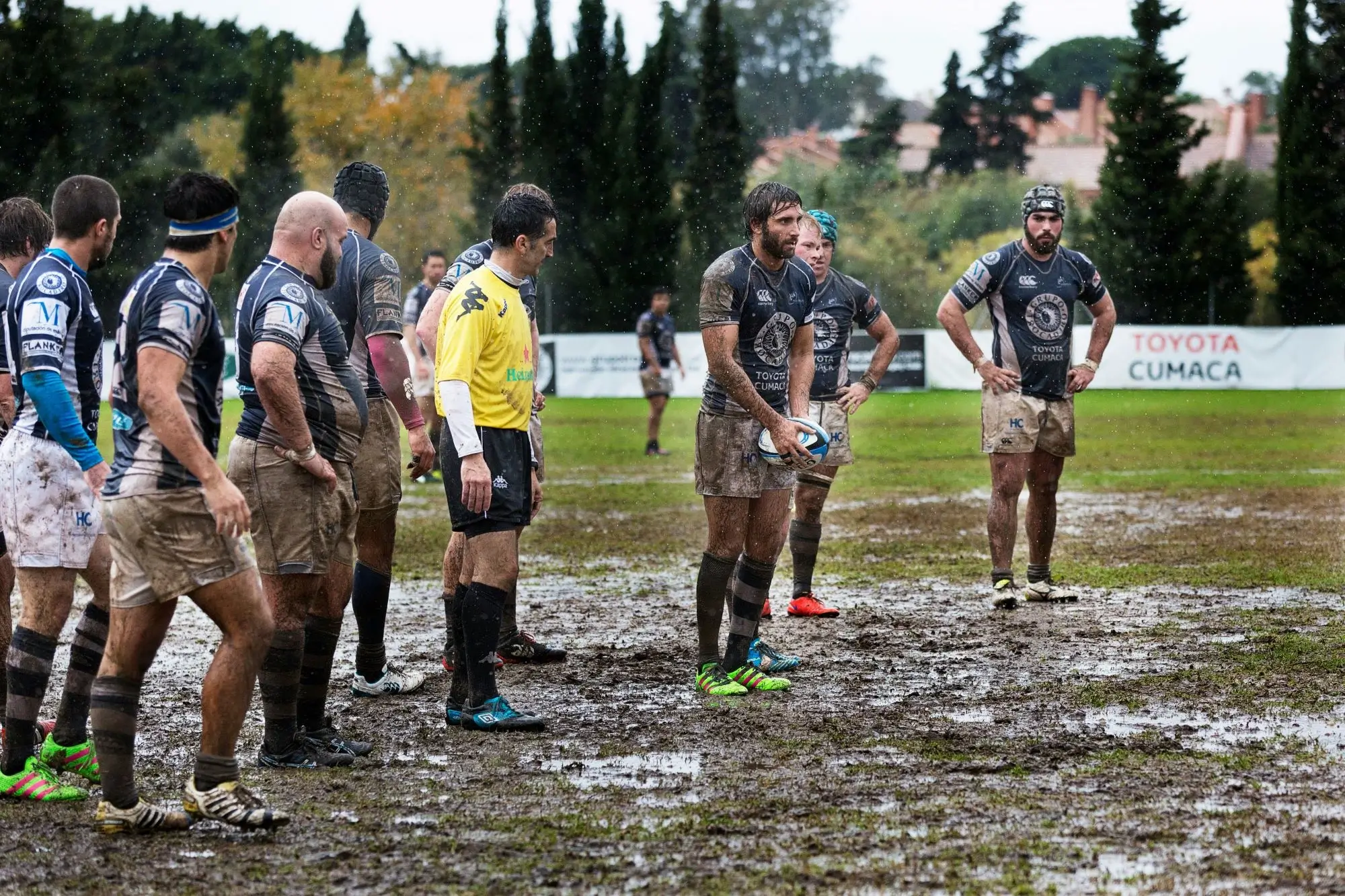A rugby player lining up to take a penalty kick on a muddy pitch in the rain