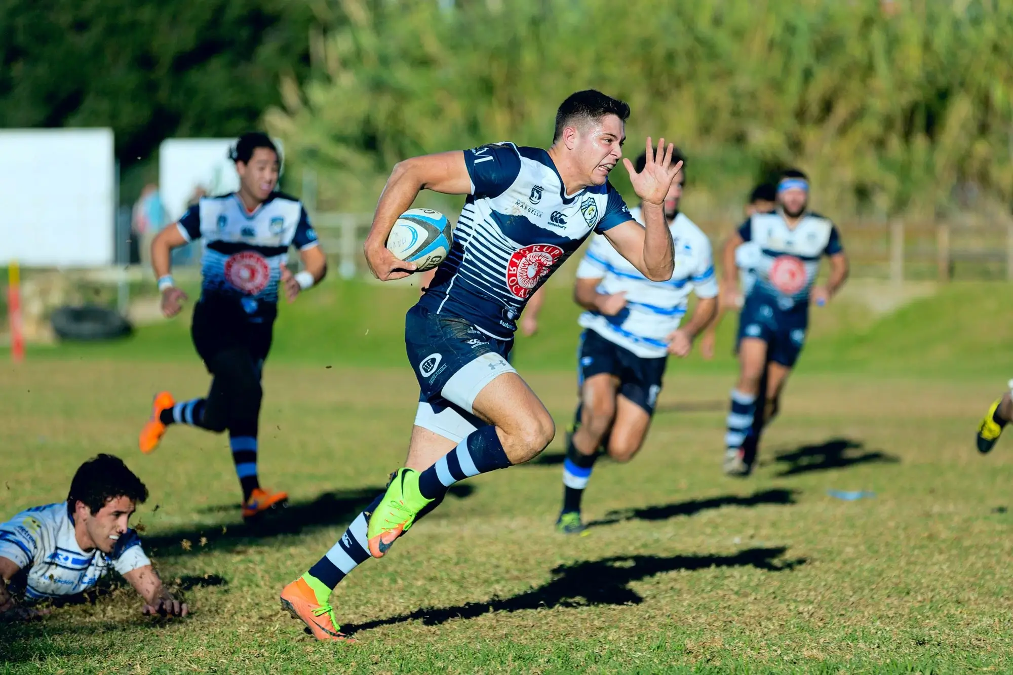 A rugby player sprinting down the pitch after avoiding a tackle