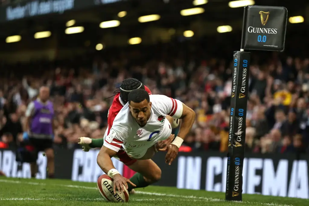 A rugby player diving to score a try while being tackled by an opposing player